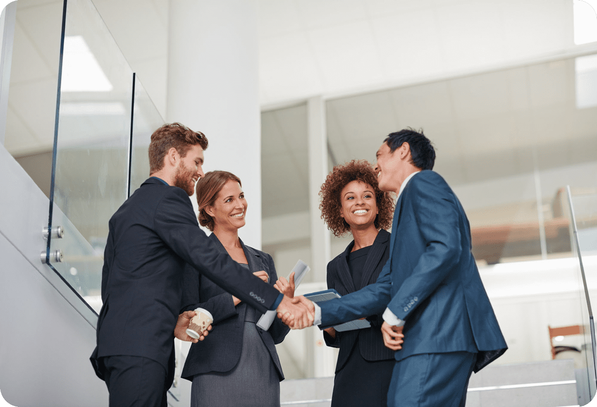 Business people shaking hands, smiling in office.